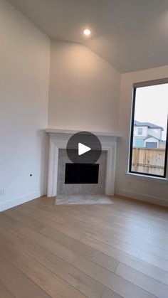 an empty living room with a fireplace and large windows