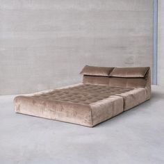 a bed that is in the middle of a room with concrete walls and flooring