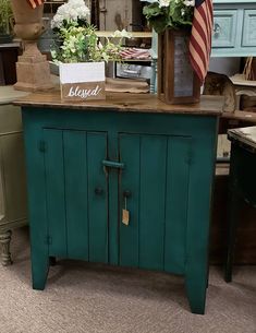 a green cabinet with an american flag on top and flowers in vases behind it