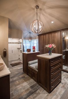 a large bathroom with wooden cabinets and marble counter tops, along with a chandelier hanging from the ceiling