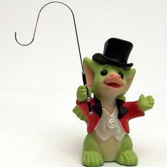 a green toy with a black hat and red jacket holding a fishing rod in its hand