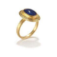 a gold ring with a blue stone in the center and a small oval shaped band around it