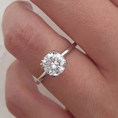 a woman's hand with a diamond ring on top of her finger, showing the center stone