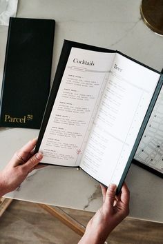 a person holding an open book on top of a table