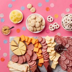 an assortment of meats, cheeses and crackers on a table with confetti