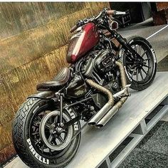 a red motorcycle parked on top of a wooden bench