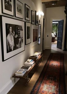 a long hallway with pictures on the wall and an area rug in front of it