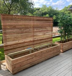 a wooden bench sitting on top of a hard wood deck next to a planter box