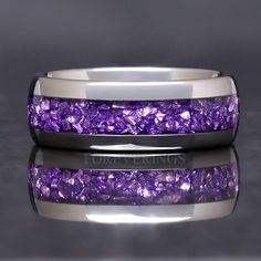 a wedding band with purple stones inlayed to the side on a reflective surface