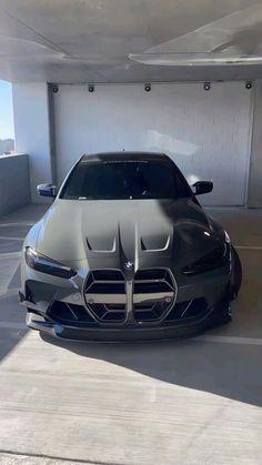 the front end of a black sports car in a parking garage