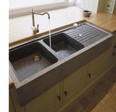 a kitchen sink with two faucets in the middle and a window behind it