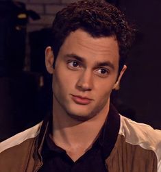 a close up of a person wearing a brown vest and black shirt with his eyes wide open