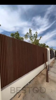 a fence that is next to a building with a sky in the backround