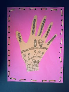 a hand made out of paper on a pink background with black and white stitchs