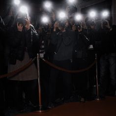 a group of people taking pictures with their cell phones in front of them at night