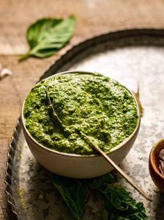 a white bowl filled with pesto on top of a metal tray