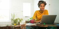 a woman sitting at a table working on her laptop