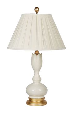 a white lamp with a gold base and shade on it's side, against a white background