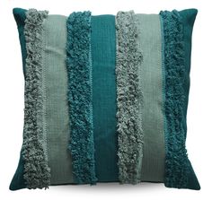 a green and grey striped pillow with fringes on the bottom, in front of a white background