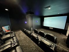 a home theater with black leather seats and a projector screen in the middle of the room