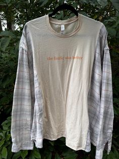 a white shirt with an orange print that says the earth was better hanging on a tree