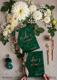 two green graduation caps with gold lettering on them, tied together by ribbon and surrounded by flowers