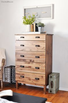 a wooden dresser sitting on top of a hard wood floor next to a white wall