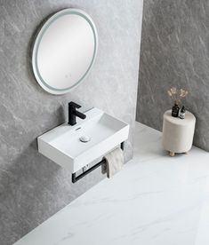 a white sink sitting next to a round mirror on a wall above a toilet paper dispenser