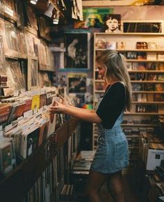 a woman is looking through records in a record shop with shelves full of vinyls