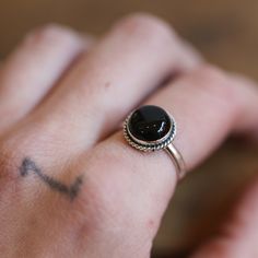 LBJ Pop Rock Ring in Black Agate Everybody loves this Black Agate ring. The black agate stone is always in fashion and always matches! Our Pop Rock Ring lets the 10mm Black Agate be the center of the show! Just right - easy to wear. Enhanced with a simple twist wire, this Black Onyx Ring stands alone or is a fantastic addition to a handful of rings. All .925 Sterling Silver. Choose your size in the drop-down below. All traditional silversmithing is done in our Baltimore Studio. Black Agate 10mm Everyday Black Onyx Rings, Black Agate Round Ring, Adjustable Onyx Rings With Black Enamel, Adjustable Black Enamel Onyx Rings, Adjustable Black Rings For Everyday Wear, Adjustable Black Round Band Jewelry, Onyx Cabochon Rings, Round Onyx Cabochon Rings, Onyx Cabochon Round Rings