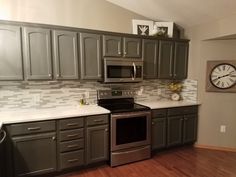 a kitchen with gray cabinets and stainless steel appliances