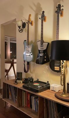 guitars are hanging on the wall next to a record player's turntable and lamp