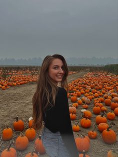 a woman standing in a field full of pumpkins