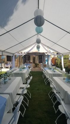 tables and chairs are set up under a tent for an outdoor function or party with white tablecloths and blue napkins