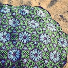 a blue and green crocheted blanket laying on the ground