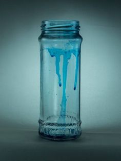 a glass jar filled with blue liquid on top of a table