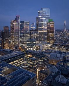 the city is lit up at night with skyscrapers in the foreground and other tall buildings