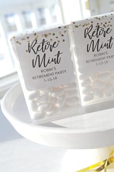 two white candy bags with gold confetti on them sitting on a cake plate