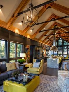 a living room filled with lots of furniture next to large windows and wooden beams on the ceiling