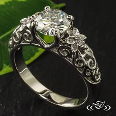 a diamond ring sitting on top of a green leaf