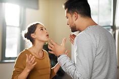 a man standing next to a woman who is touching her face with both hands and looking up