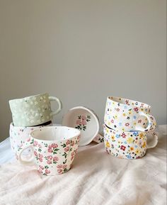 four cups and saucers are sitting on a bed