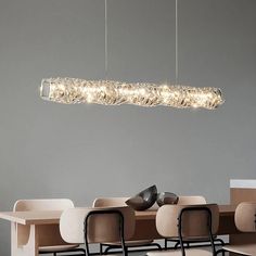 a modern light fixture hanging from the ceiling over a long table with chairs and desks