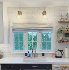 a kitchen with white tile and black cabinets is pictured in this image, there are two windows above the sink