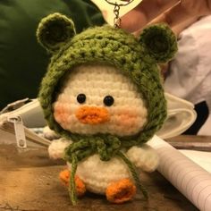 a crocheted penguin keychain with a green hat and scarf around it's neck