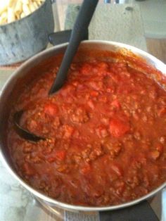 a pot full of chili sitting on top of a stove with a spoon in it