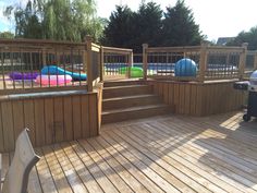 a wooden deck with hot tubs and inflatable balls on the other side