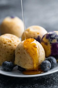 blueberry cheesecake bites being drizzled with syrup on a white plate