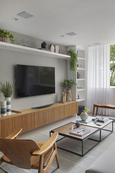 a living room filled with furniture and a flat screen tv mounted on a wall next to a window