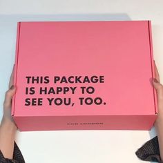 a person holding a pink box that says, this package is happy to see you, too